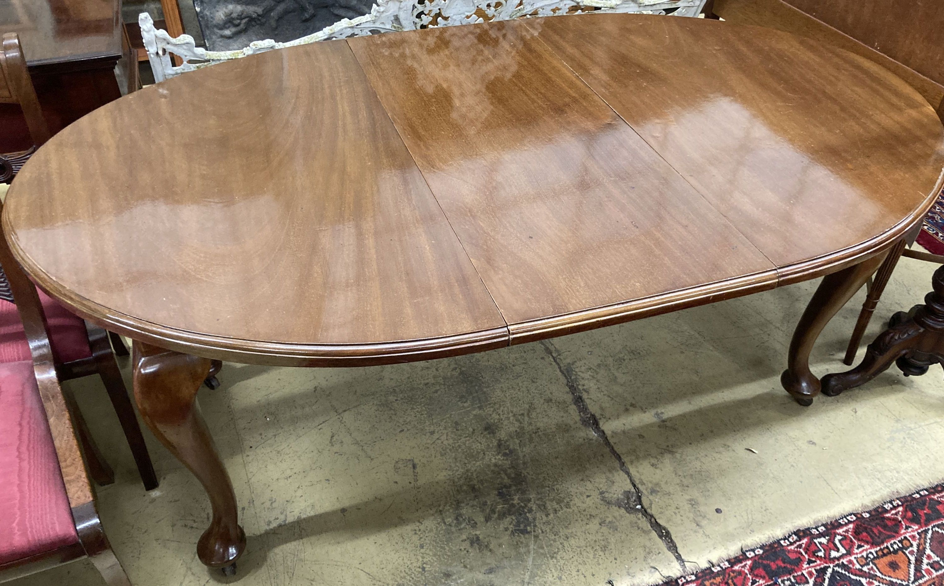 A 1930s mahogany oval topped extending dining table, one spare leaf, 174cm extended, width 106cm, height 73cm and winder